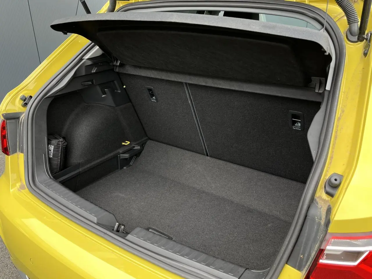Coffre ouvert vu de l'arrière droit d'une Audi A1 Allstreet jaune Python, montrant l'espace de chargement vide.