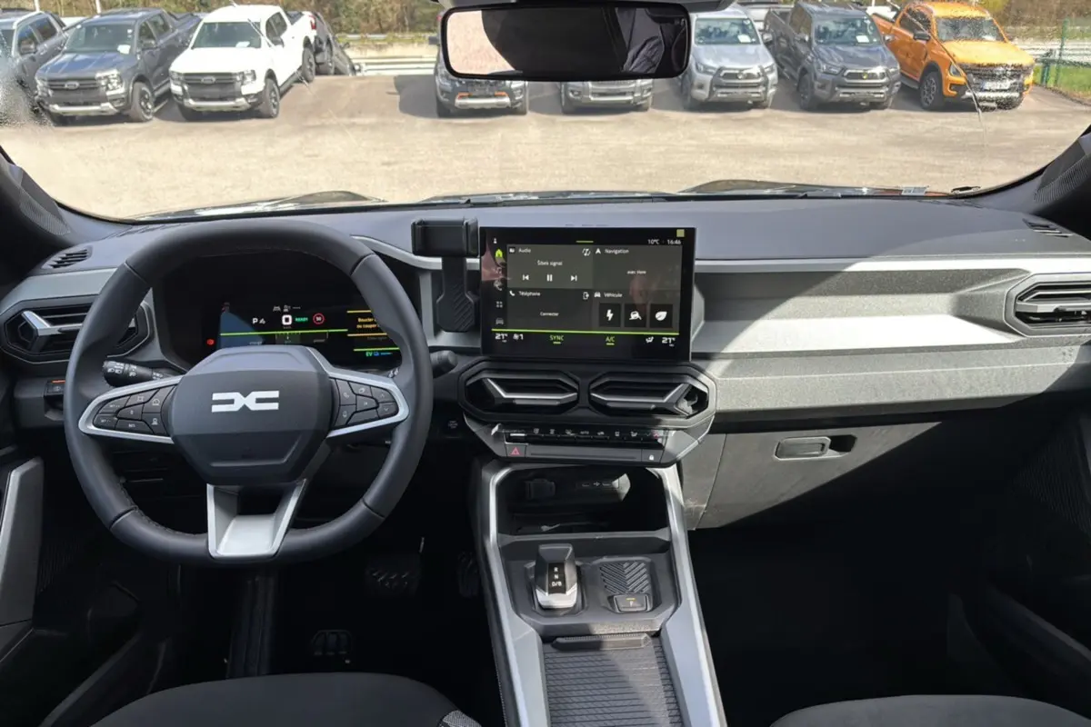 Vue intérieure du tableau de bord et volant cuir du Dacia Bigster Hybrid 155 Journey Plus avec écran tactile 10,1 pouces.