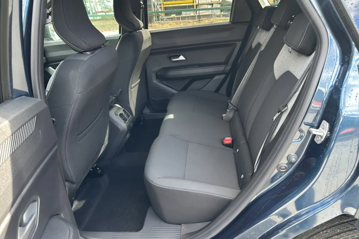 Vue côté gauche sur l’arrière intérieur du Dacia Bigster bleu indigo, montrant la banquette arrière noire et les portes ouvertes.