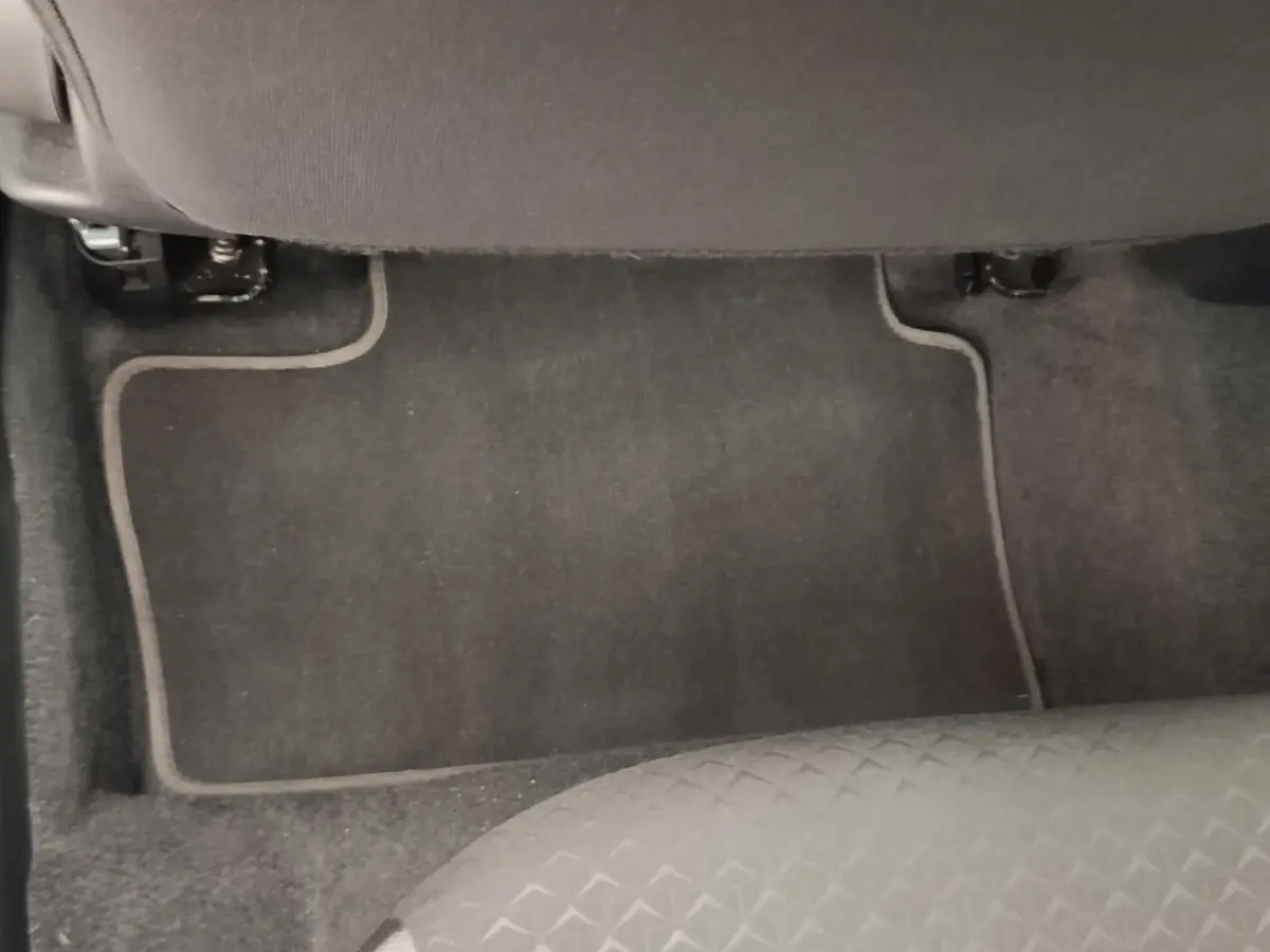 Vue rapprochée du tapis de sol gris foncé et de la partie inférieure du siège avant d’un Nissan Juke gris clair.