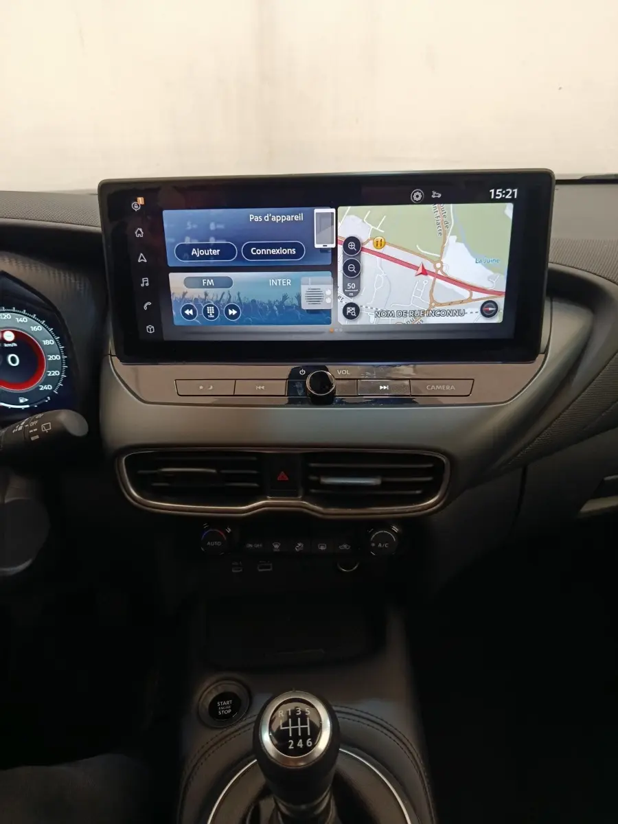 Vue intérieure centrée sur la console centrale du Nissan Juke gris clair 2025 avec écran tactile et boîte manuelle.