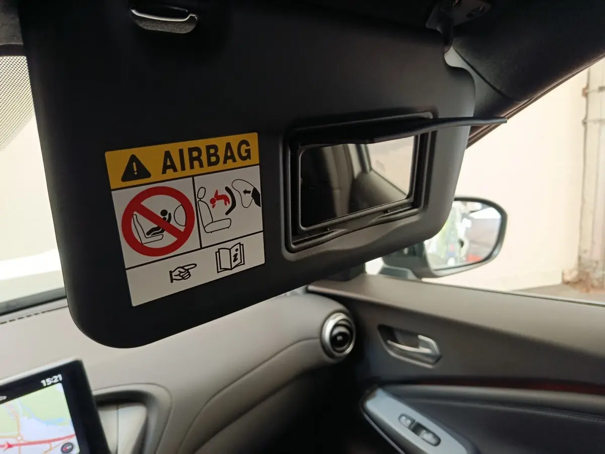 Vue intérieure du pare-soleil côté conducteur avec miroir et avertissement airbag dans un Nissan Juke gris clair.