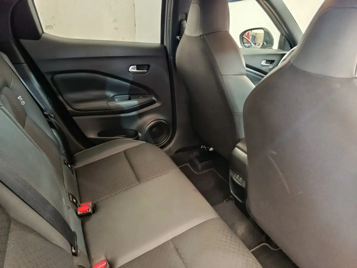 Vue intérieure côté gauche sur la banquette arrière noire du Nissan Juke 2025 avec ceintures et porte arrière visible.
