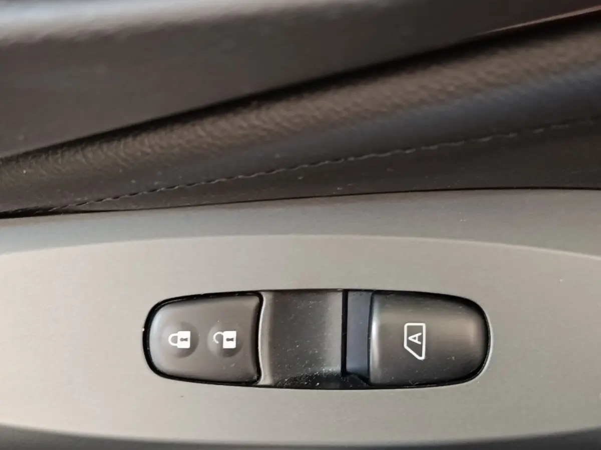 Gros plan sur les boutons de verrouillage central et de démarrage automatique du moteur dans un Nissan Juke gris clair 2025.