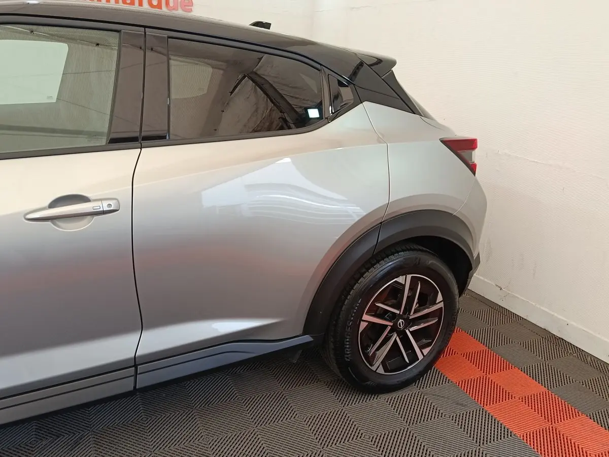 Vue latérale côté gauche sur l'arrière d'un Nissan Juke gris clair avec jante alliage noire et toit noir.
