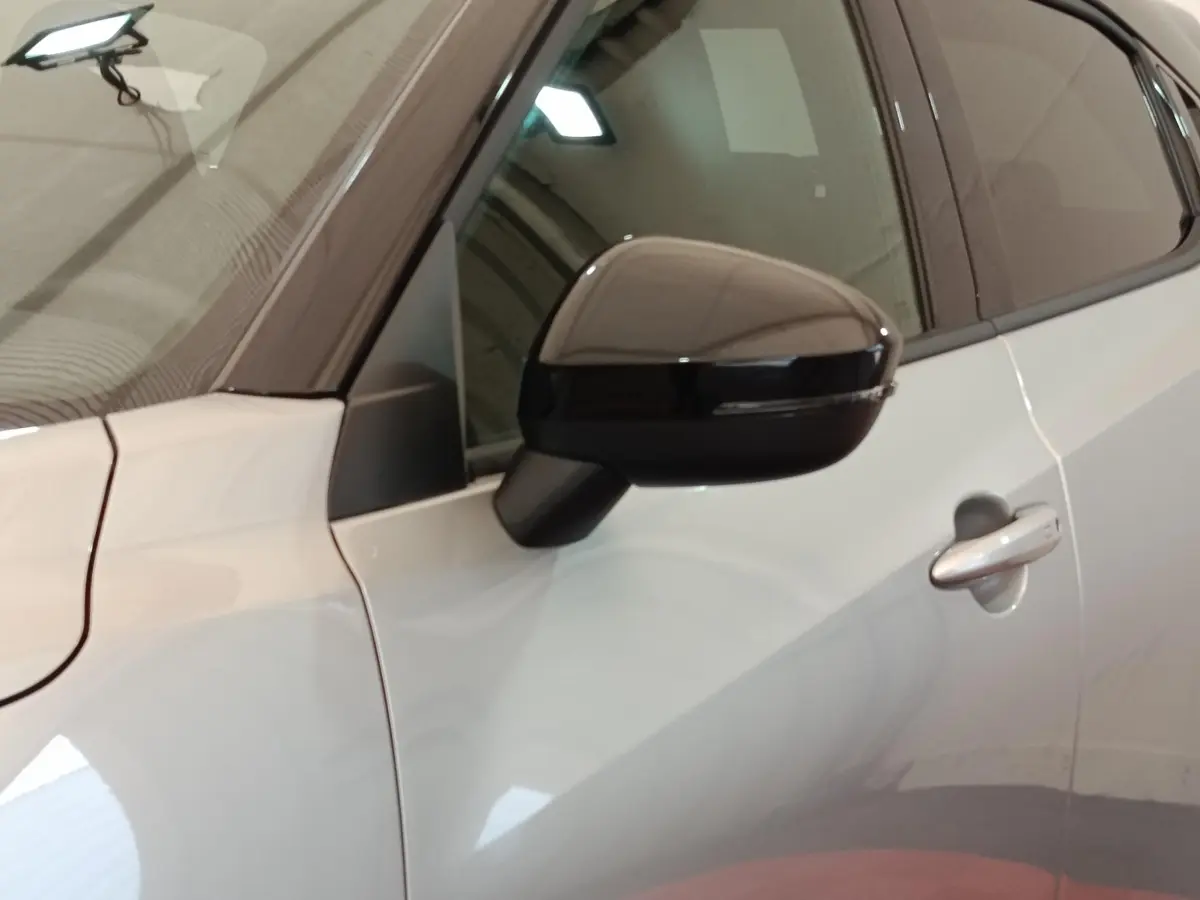 Vue rapprochée du rétroviseur et de la portière côté gauche d’un Nissan Juke gris clair 2025.