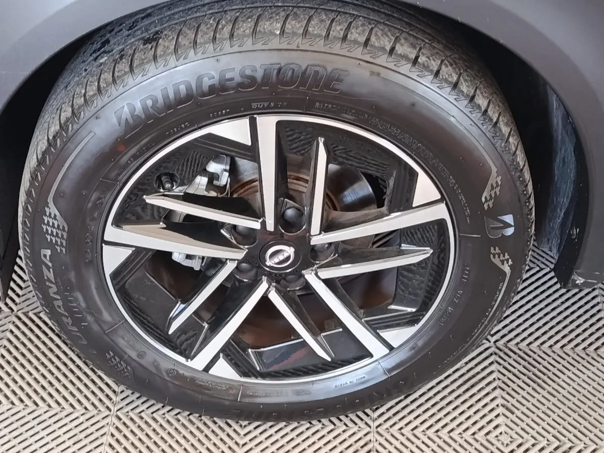 Gros plan sur la jante alliage noire et argentée du Nissan Juke gris clair, avec pneu Bridgestone visible.