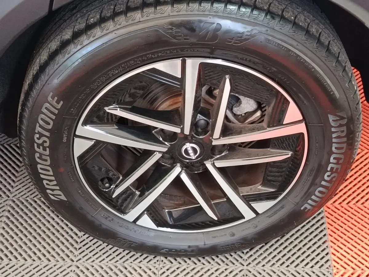 Gros plan sur la jante noire et argentée d’un Nissan Juke gris clair avec pneu Bridgestone visible de face.