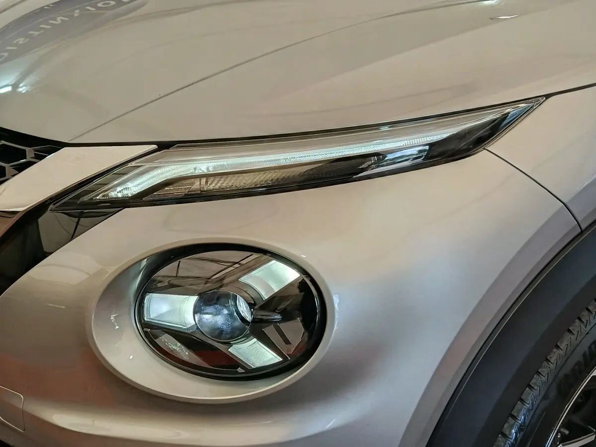 Gros plan sur le phare avant droit du Nissan Juke gris clair 2025, mettant en valeur ses feux LED distinctifs.