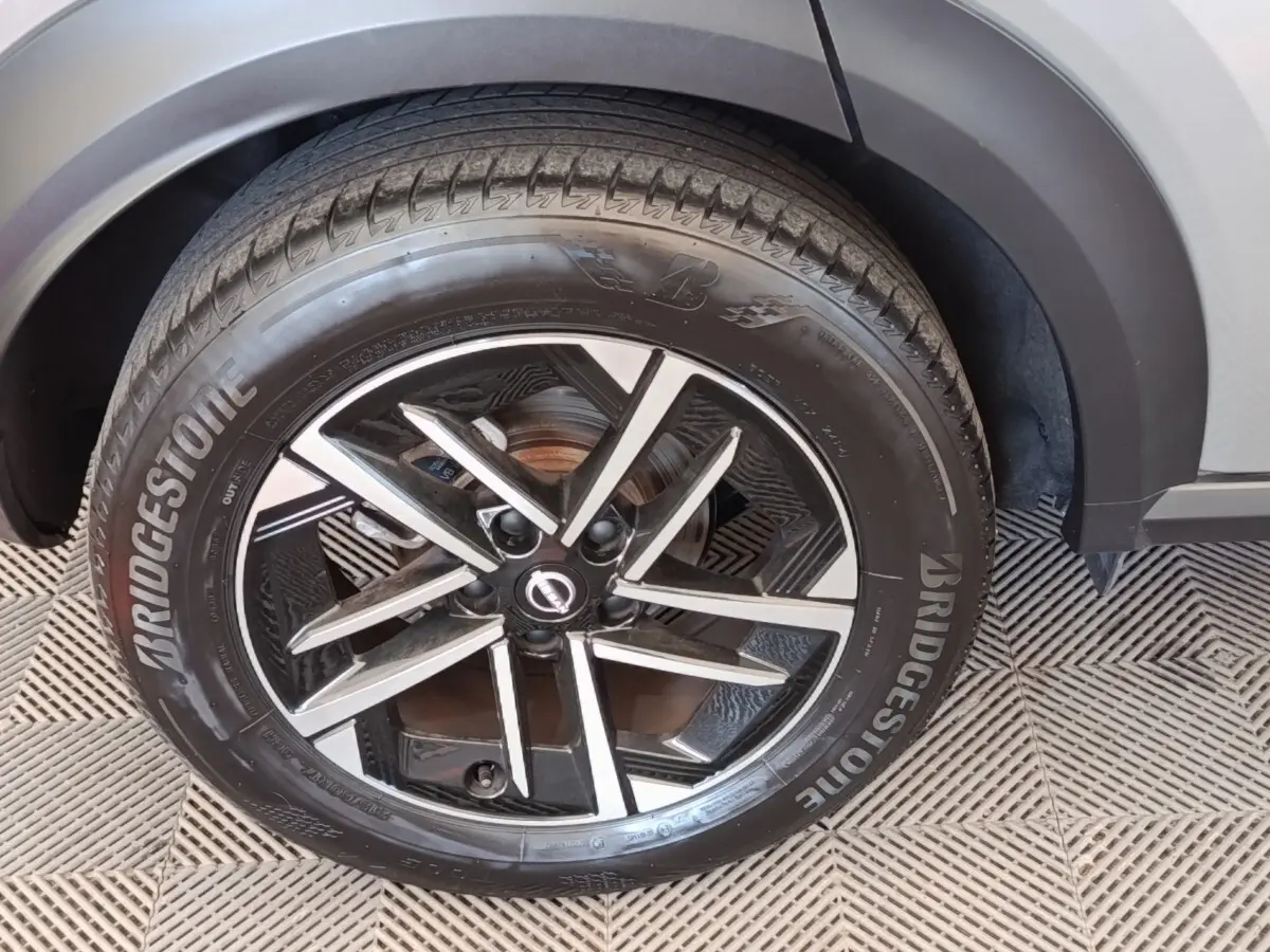 Gros plan sur la roue avant droite du Nissan Juke gris clair 2025 avec jante alliage noire et argentée Bridgestone.