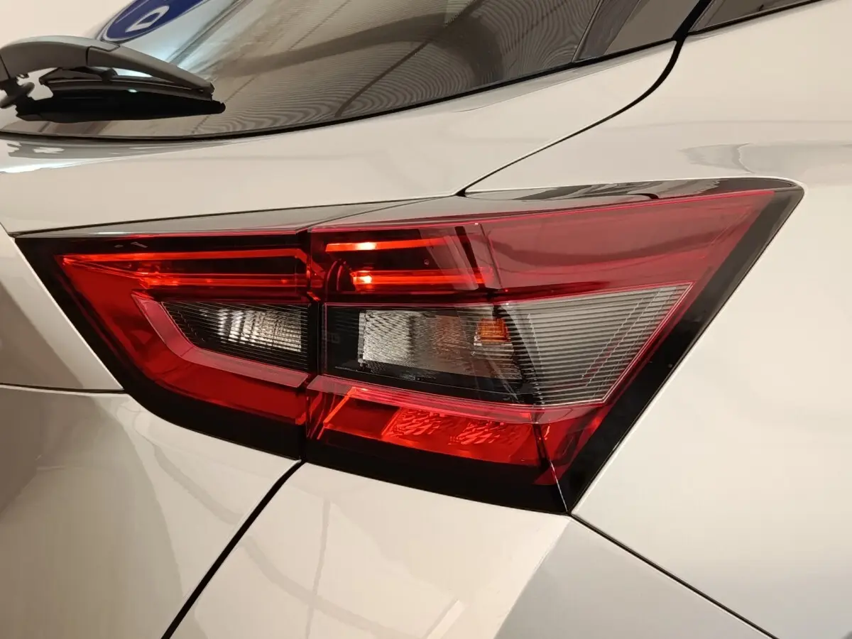 Gros plan sur le feu arrière droit rouge et blanc d’un Nissan Juke gris clair 2025, vue de profil arrière.