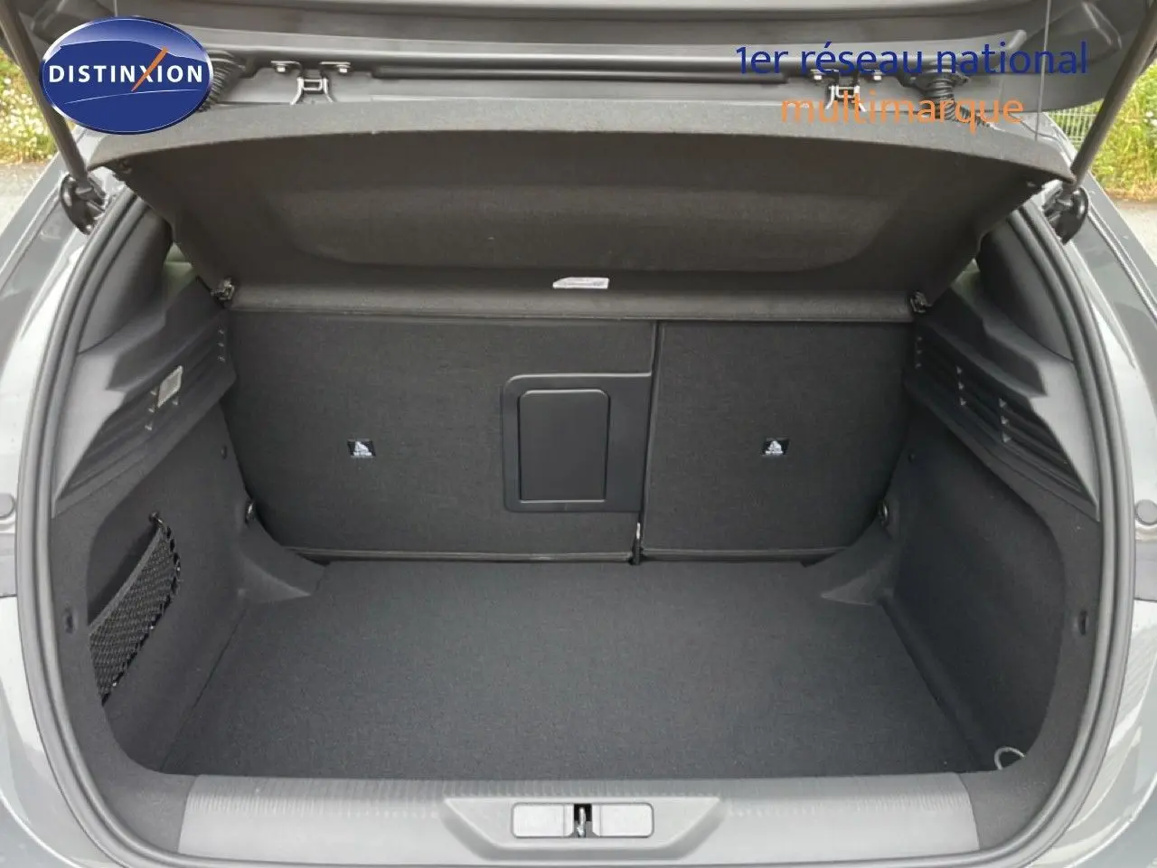 Coffre ouvert vu de l'arrière d'une Peugeot 308 gris selenium metal, espace de chargement propre et spacieux.