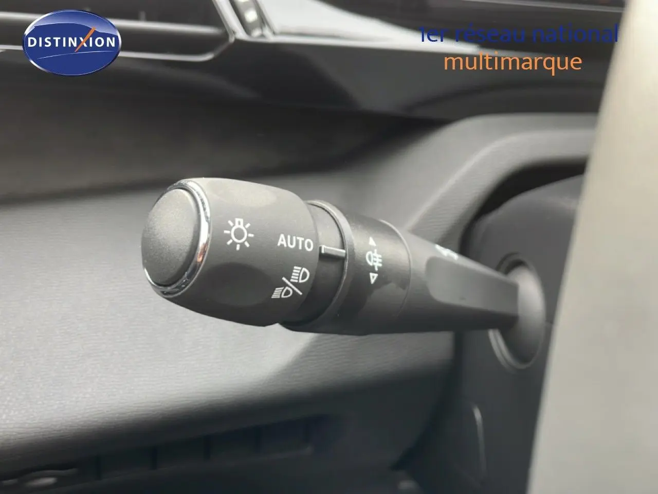 Gros plan sur la commande des phares du Peugeot 308 gris selenium métal, intérieur noir, vue côté gauche du volant.
