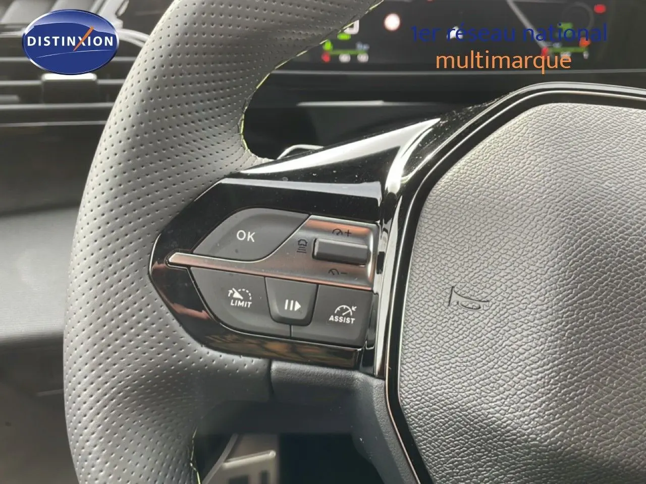 Gros plan sur le volant perforé côté gauche du Peugeot 308 gris Selenium, avec commandes de régulateur et assistant.