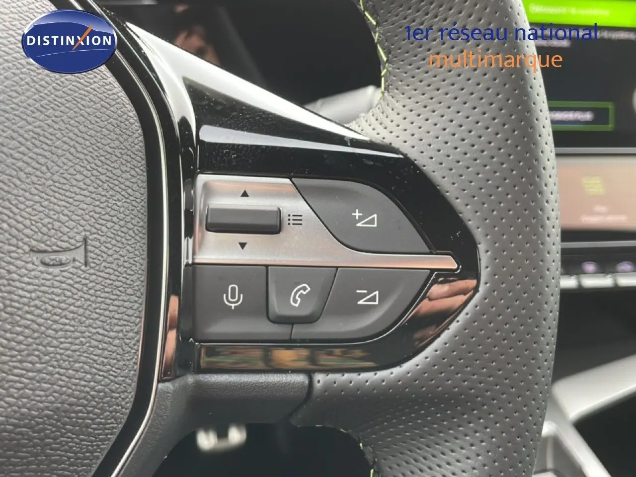 Gros plan sur les commandes à gauche du volant perforé d'une Peugeot 308 gris selenium 2026, avec boutons de volume et téléphone.