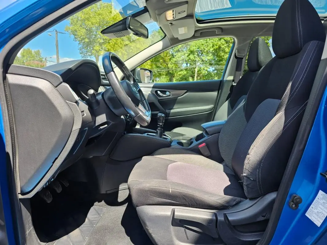 Intérieur côté conducteur du Nissan Qashqai bleu 2019, montrant le volant, la boîte manuelle et les sièges tissu noirs.