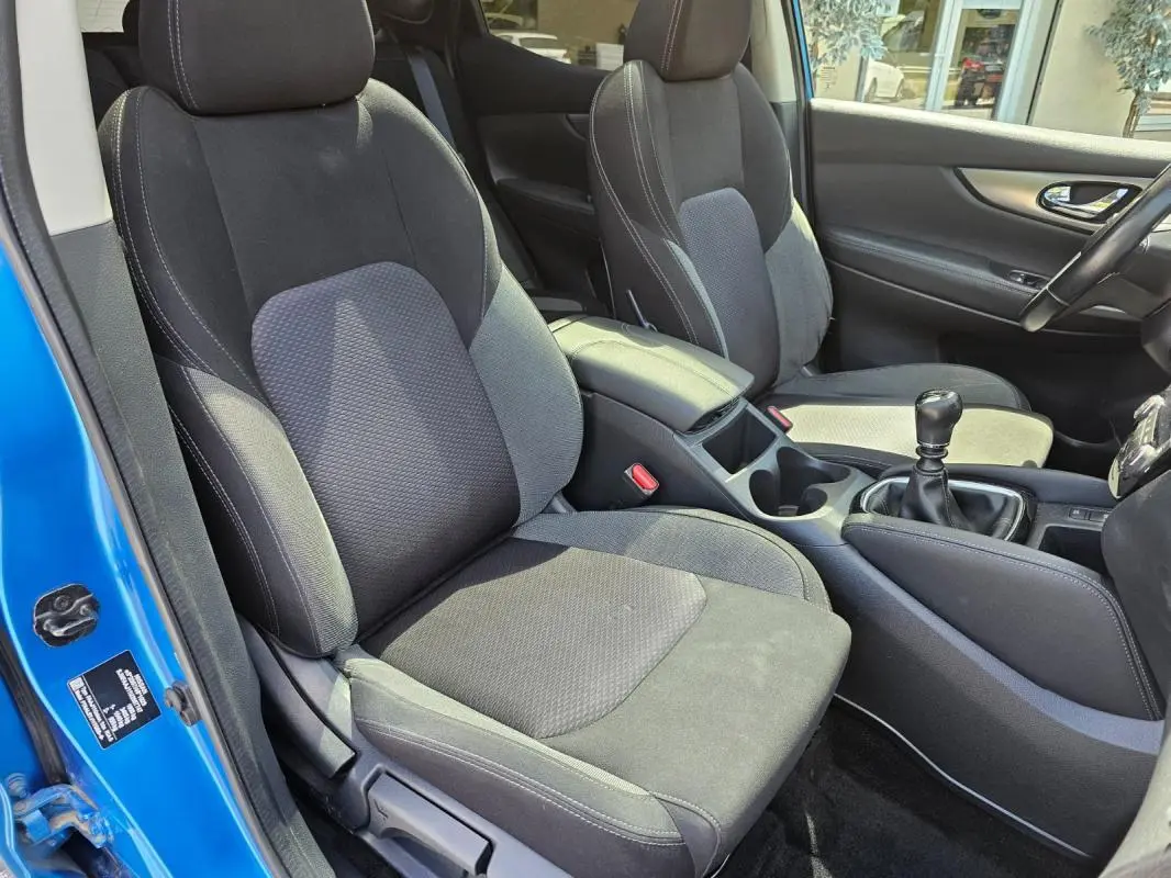 Vue intérieure côté conducteur du Nissan Qashqai bleu 2019, montrant les sièges noirs et la boîte manuelle.