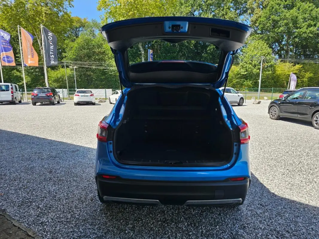 Vue arrière d’un Nissan Qashqai bleu 2019 avec coffre ouvert, montrant l’espace de chargement vide.