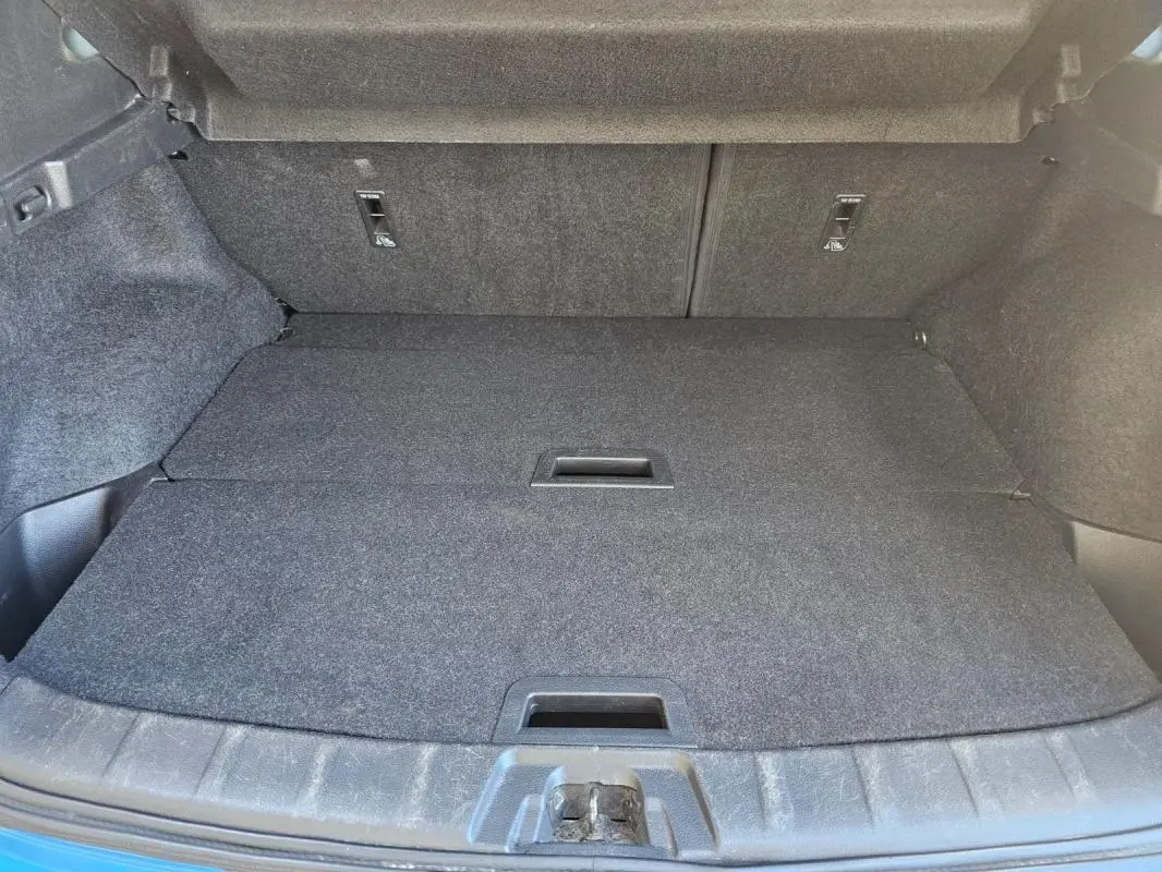 Coffre ouvert du Nissan Qashqai bleu 2019, vue intérieure montrant le plancher plat et les fixations arrière.