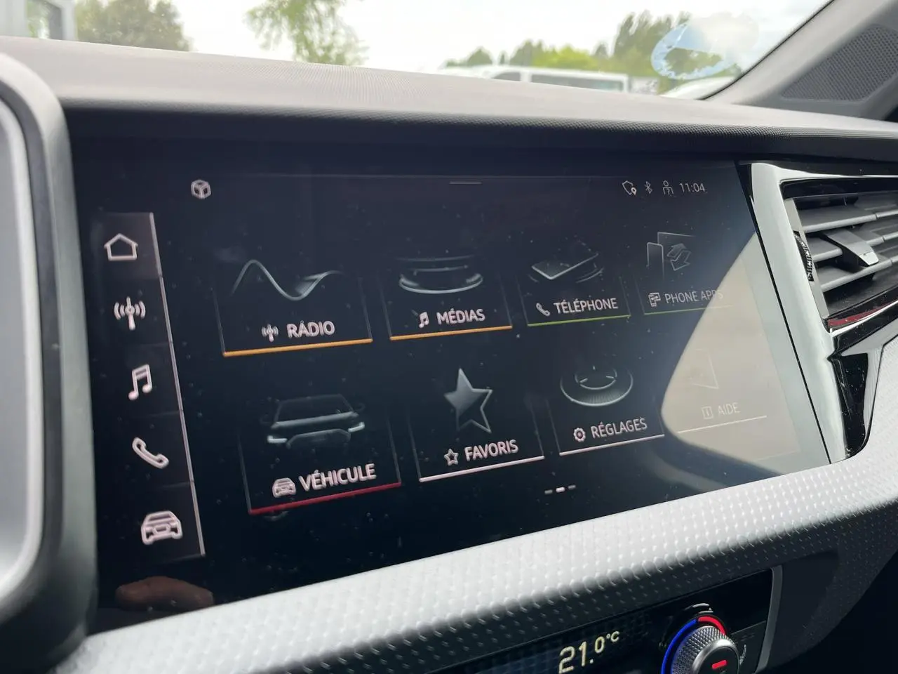Écran tactile central de l'Audi A1 Sportback 25 TFSI rouge Misano, affichant le menu multimédia et réglages.