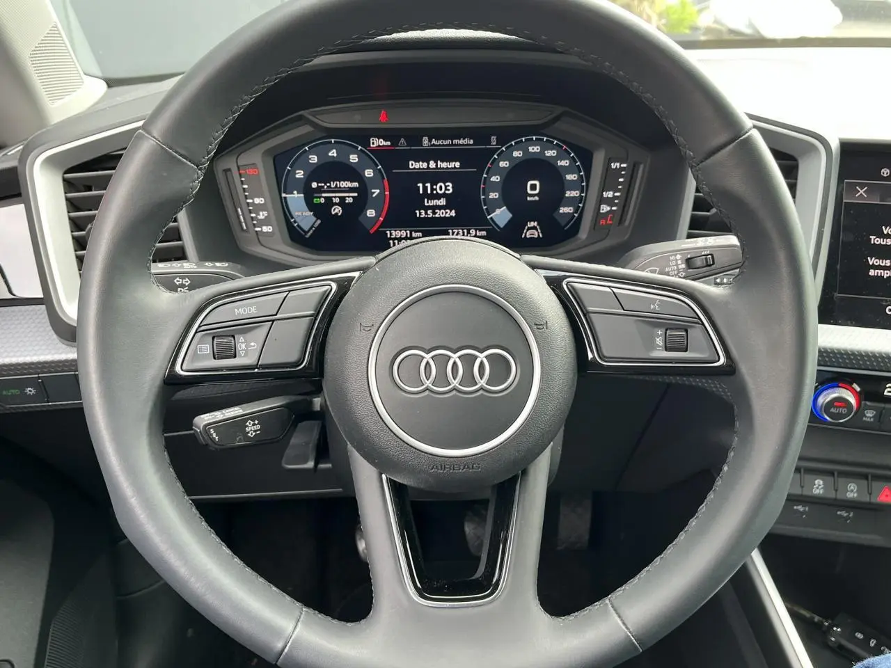 Vue intérieure centrée sur le volant cuir multifonctions et la console centrale de l'Audi A1 Sportback 25 TFSI rouge Misano 2022.