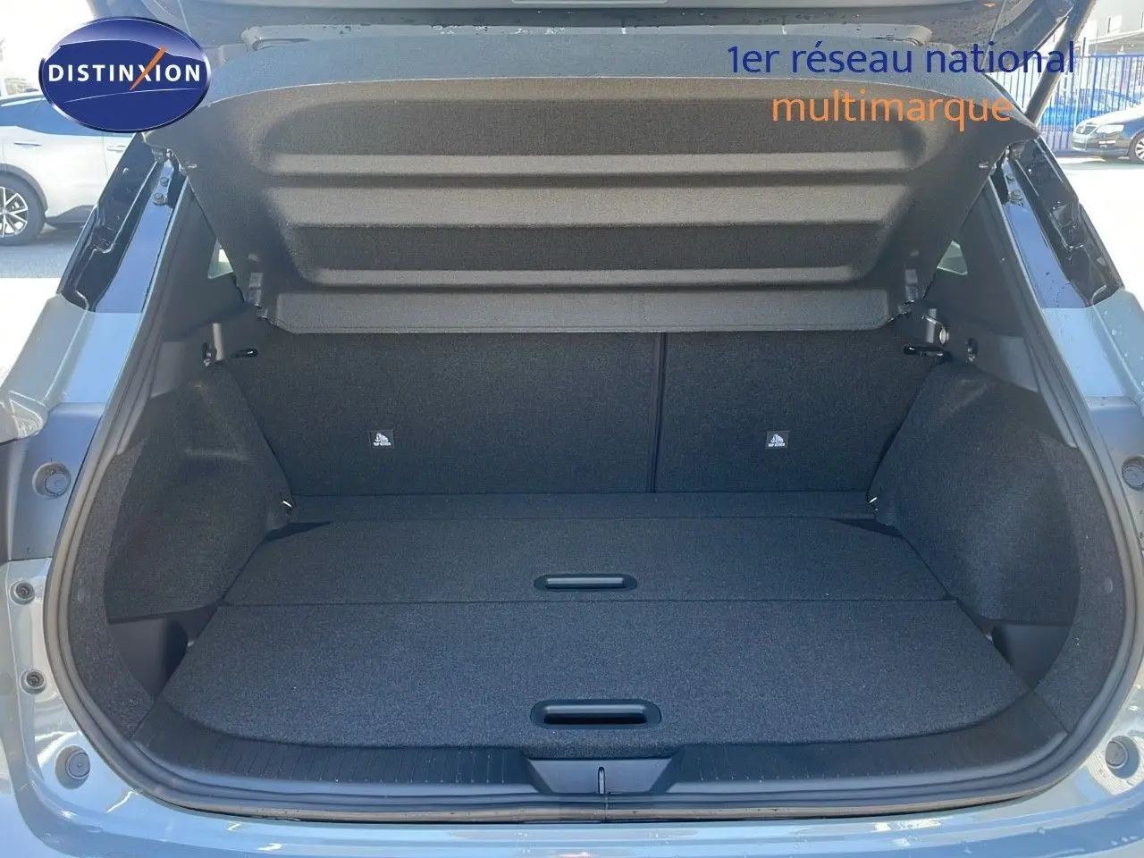 Coffre ouvert du Nissan Qashqai 2025 gris céramique avec toit noir, vue arrière montrant l'espace de chargement vide.