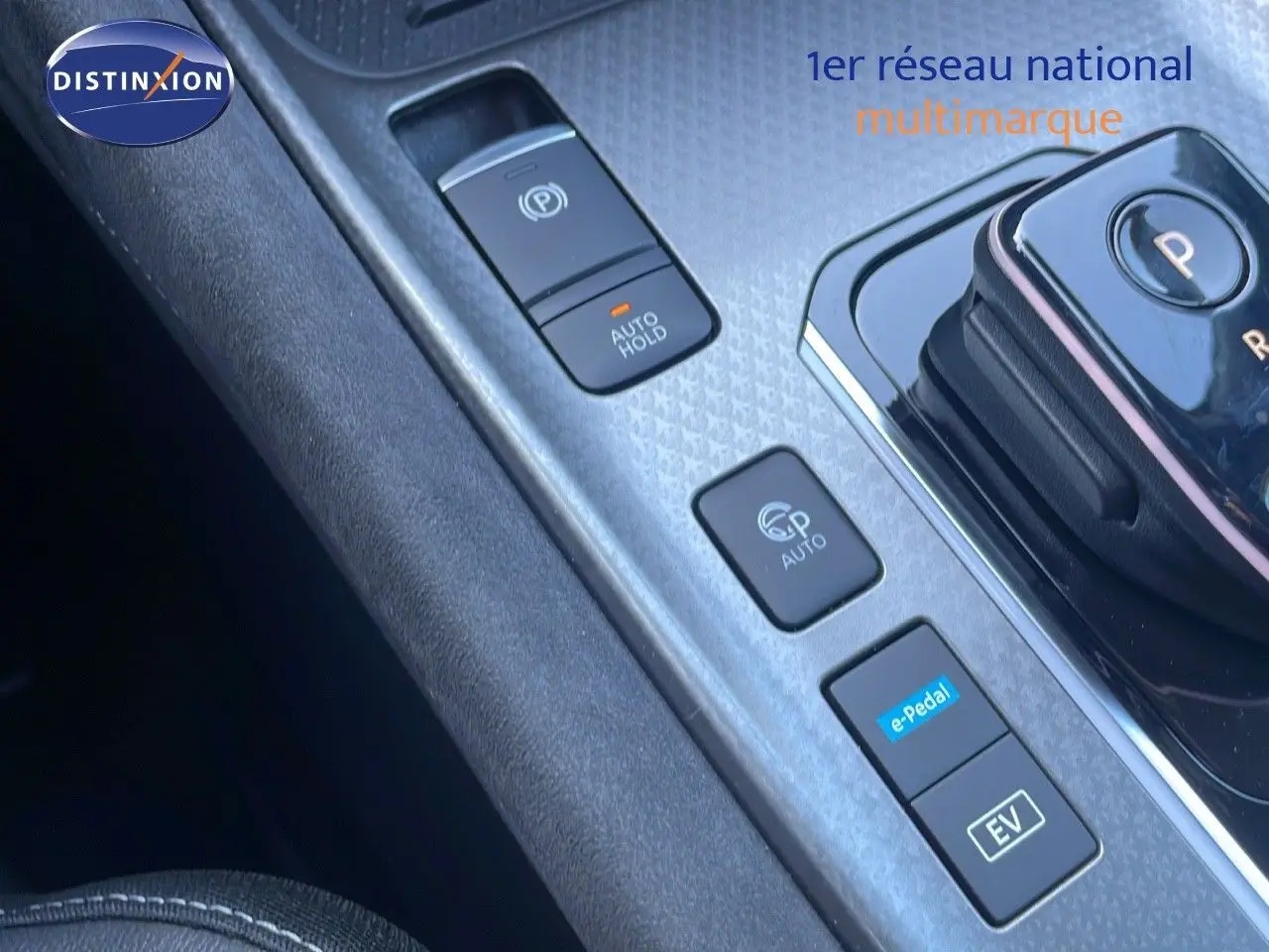 Gros plan sur la console centrale du Nissan Qashqai gris céramique, mettant en valeur les commandes de boîte automatique et modes de conduite électrique.