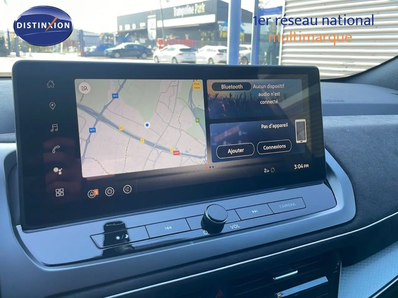 Vue rapprochée de l'écran tactile central du Nissan Qashqai 2025 gris céramique avec toit noir, affichant la navigation et Bluetooth.