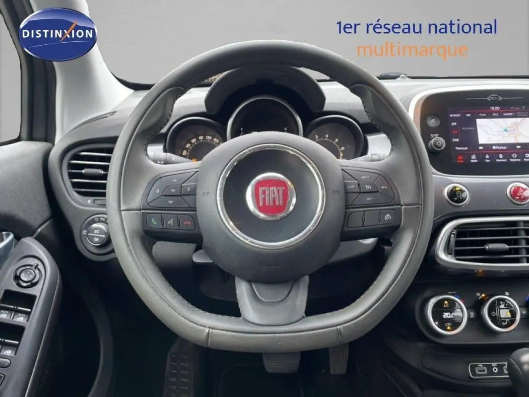 Vue intérieure centrée sur le volant FIAT d'une 500X MY18, avec tableau de bord et écran tactile visibles.