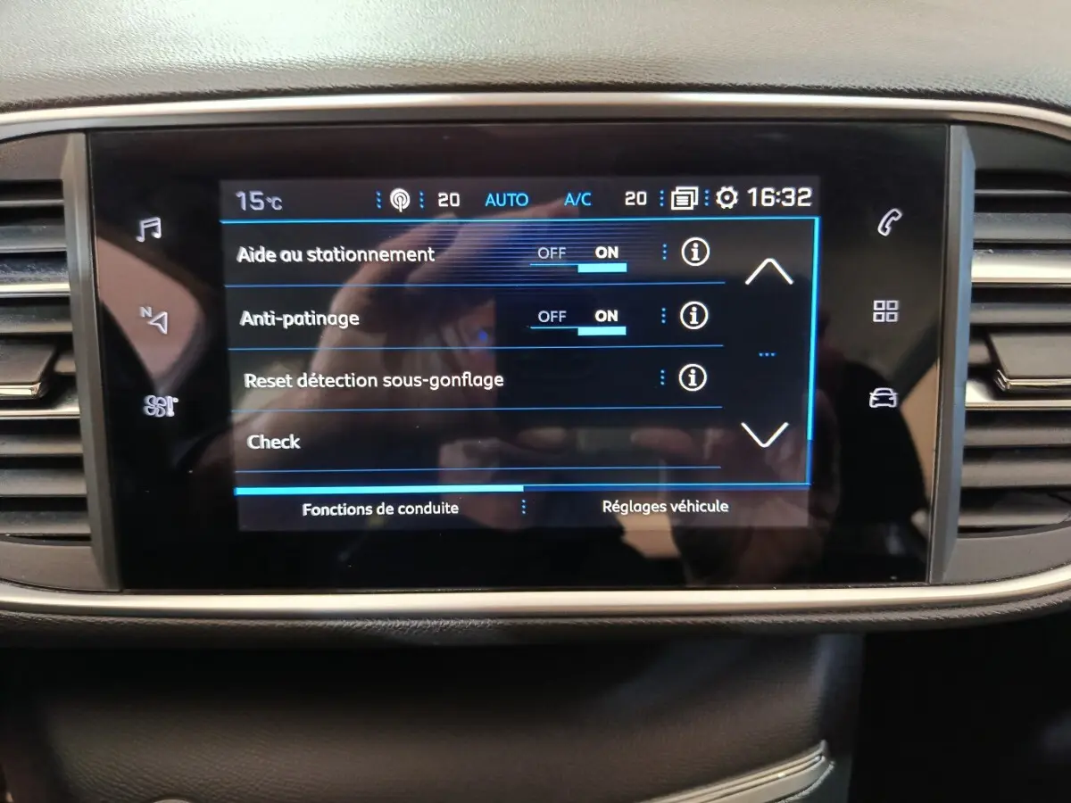 Écran tactile central de la Peugeot 308 blanc, affichant les réglages d'aide au stationnement et antipatinage.