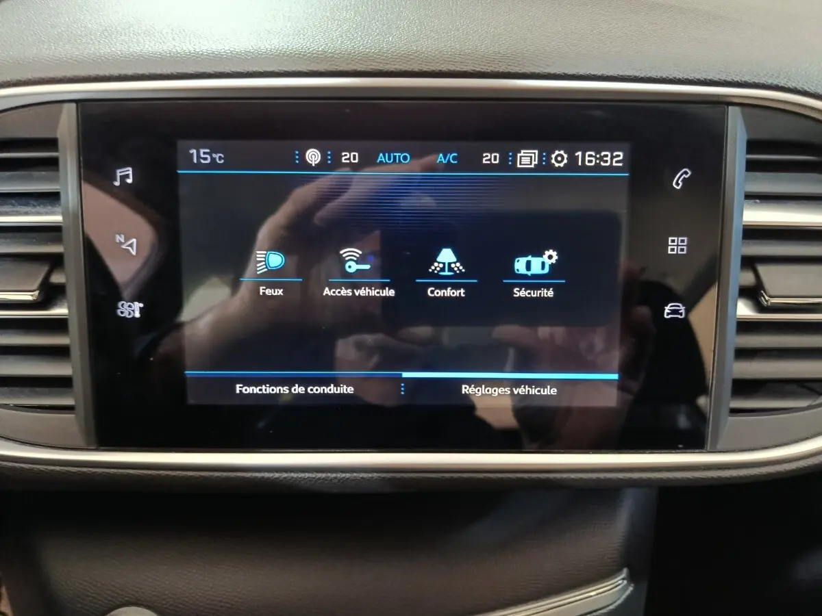 Écran tactile central affichant les réglages de conduite et véhicule dans l'habitacle d'une Peugeot 308 blanche.