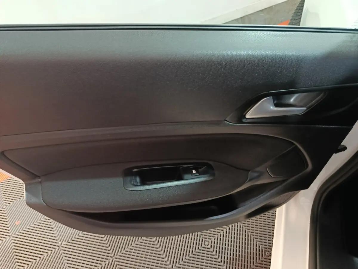 Vue rapprochée de la porte avant gauche noire de la Peugeot 308 blanche, mettant en valeur la poignée et le bouton de verrouillage.