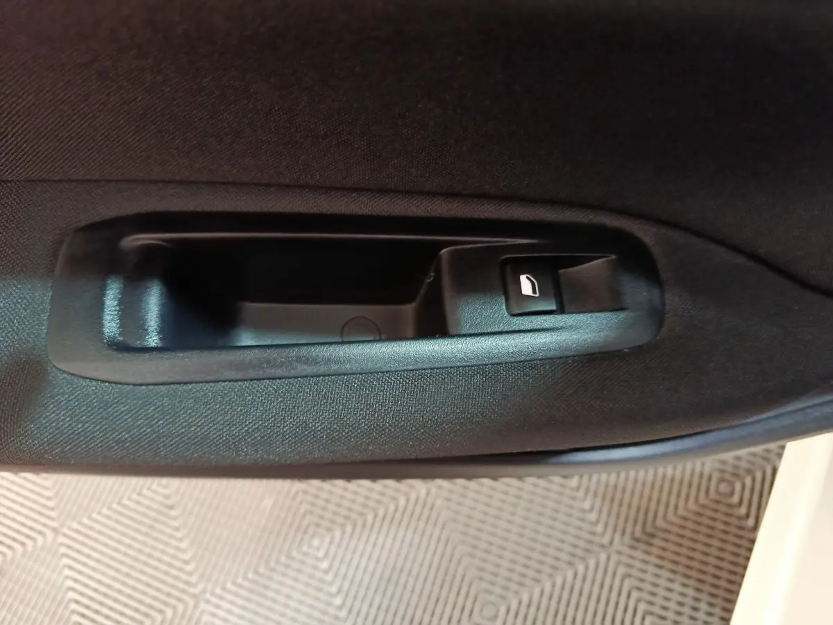 Gros plan sur la poignée intérieure noire de la porte côté gauche d'une Peugeot 308 blanche de 2021.