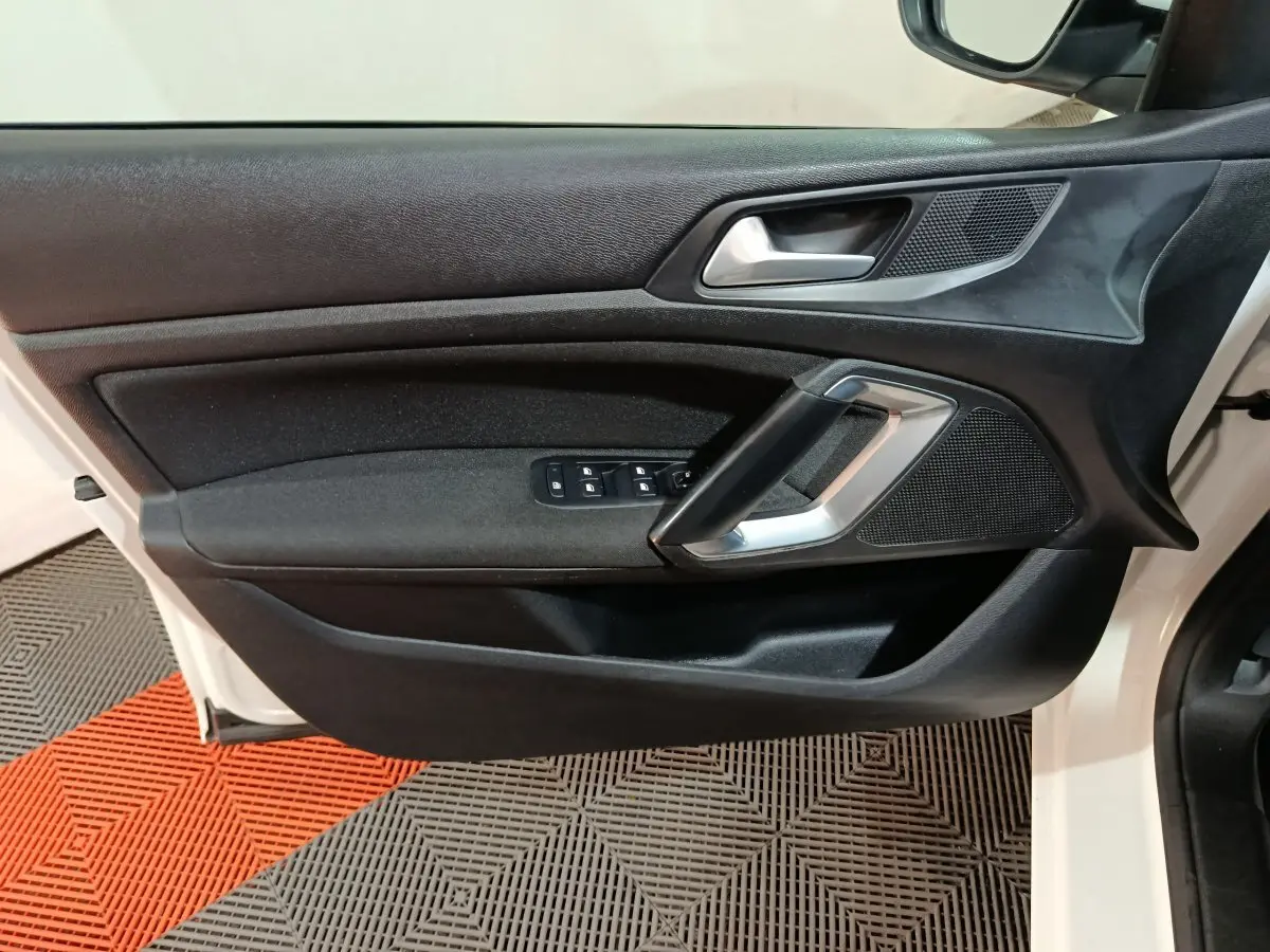 Vue rapprochée de la porte avant gauche blanche du Peugeot 308 2021, avec commandes électriques et poignée argentée.