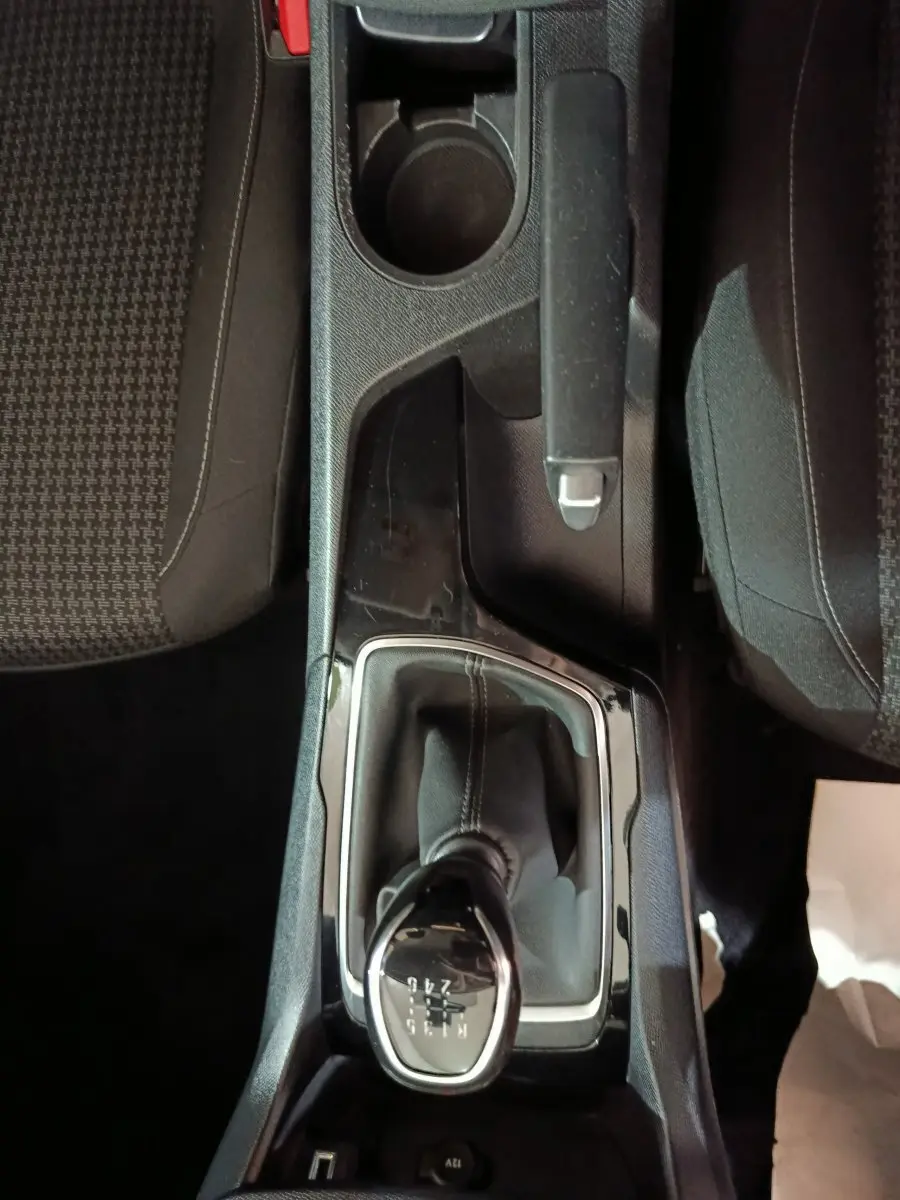 Vue plongeante sur la console centrale noire de la Peugeot 308 blanche, mettant en valeur le levier de vitesse manuel.