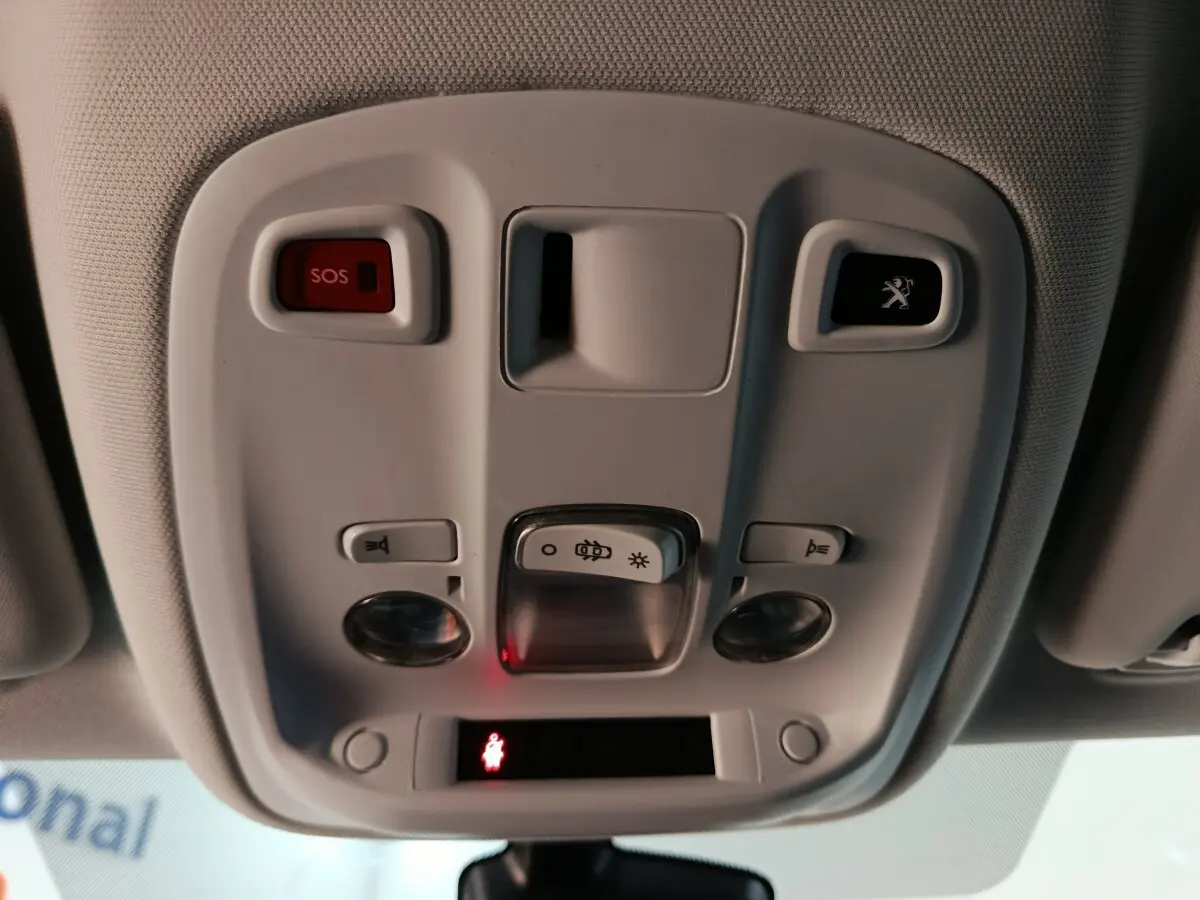 Vue en gros plan du plafonnier intérieur blanc avec bouton SOS et logo Peugeot éclairé sur une Peugeot 308 blanche.