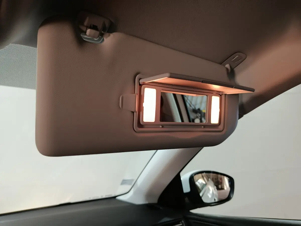 Miroir de courtoisie éclairé sur pare-soleil côté conducteur dans l'habitacle clair d'une Peugeot 308 blanche.