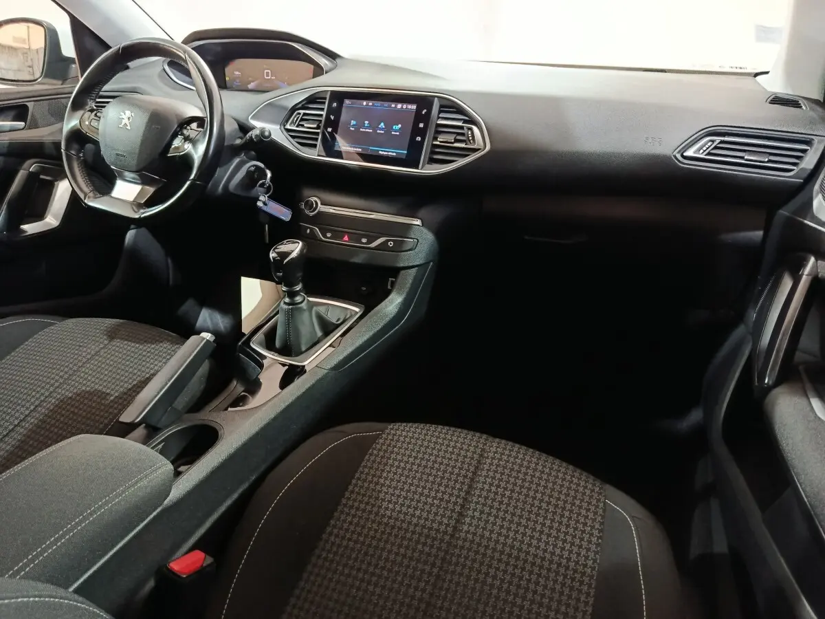 Intérieur noir de la Peugeot 308 BlueHDi 130, vue côté conducteur montrant volant cuir et écran tactile central.