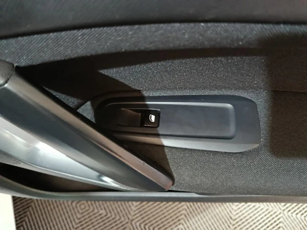 Gros plan sur la commande de lève-vitre côté gauche d'une Peugeot 308 blanche, intérieur tissu noir.