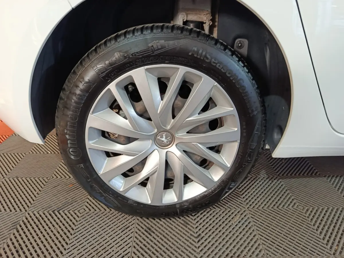 Gros plan sur la roue avant gauche d’une Peugeot 308 blanche, mettant en valeur la jante en alliage et le pneu Continental.