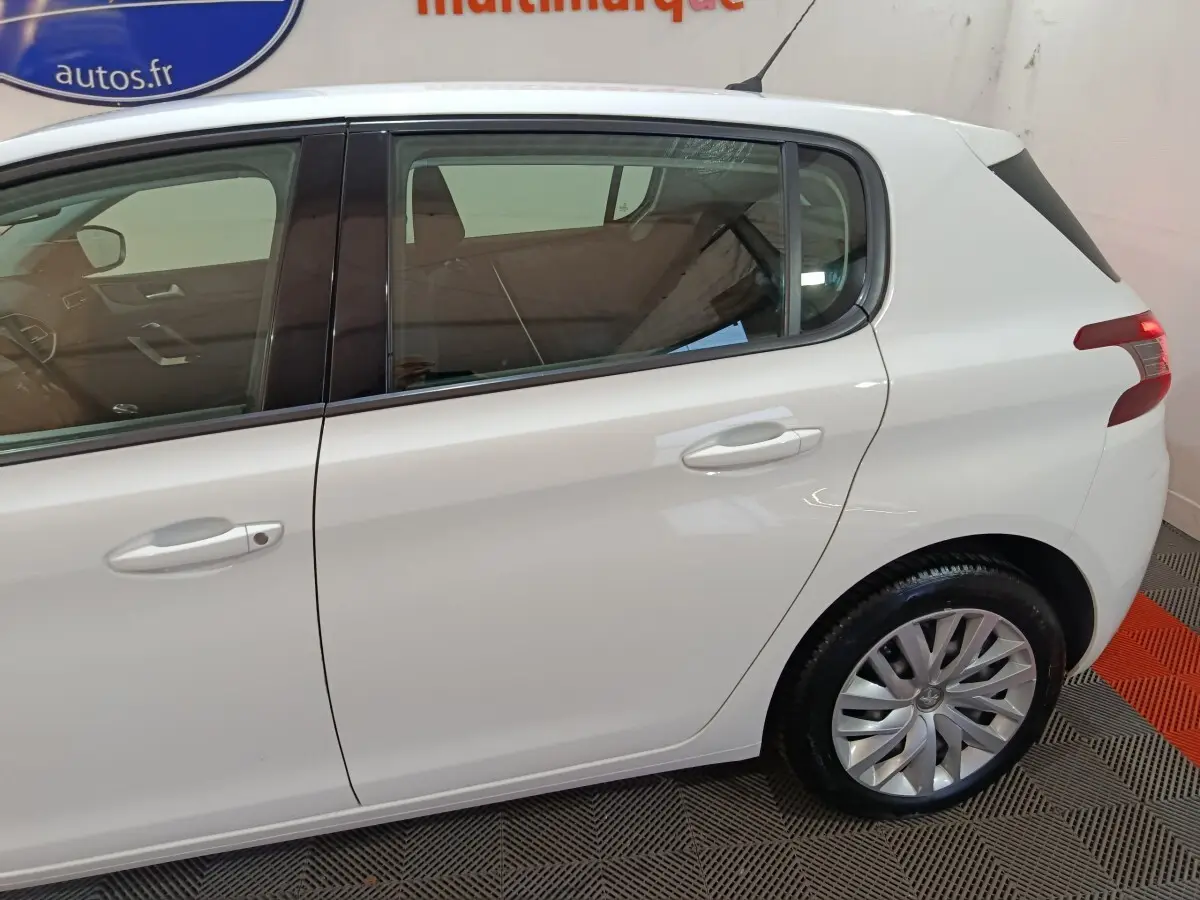 Vue latérale côté droit d'une Peugeot 308 blanche, mettant en valeur les portes arrière et la roue arrière.