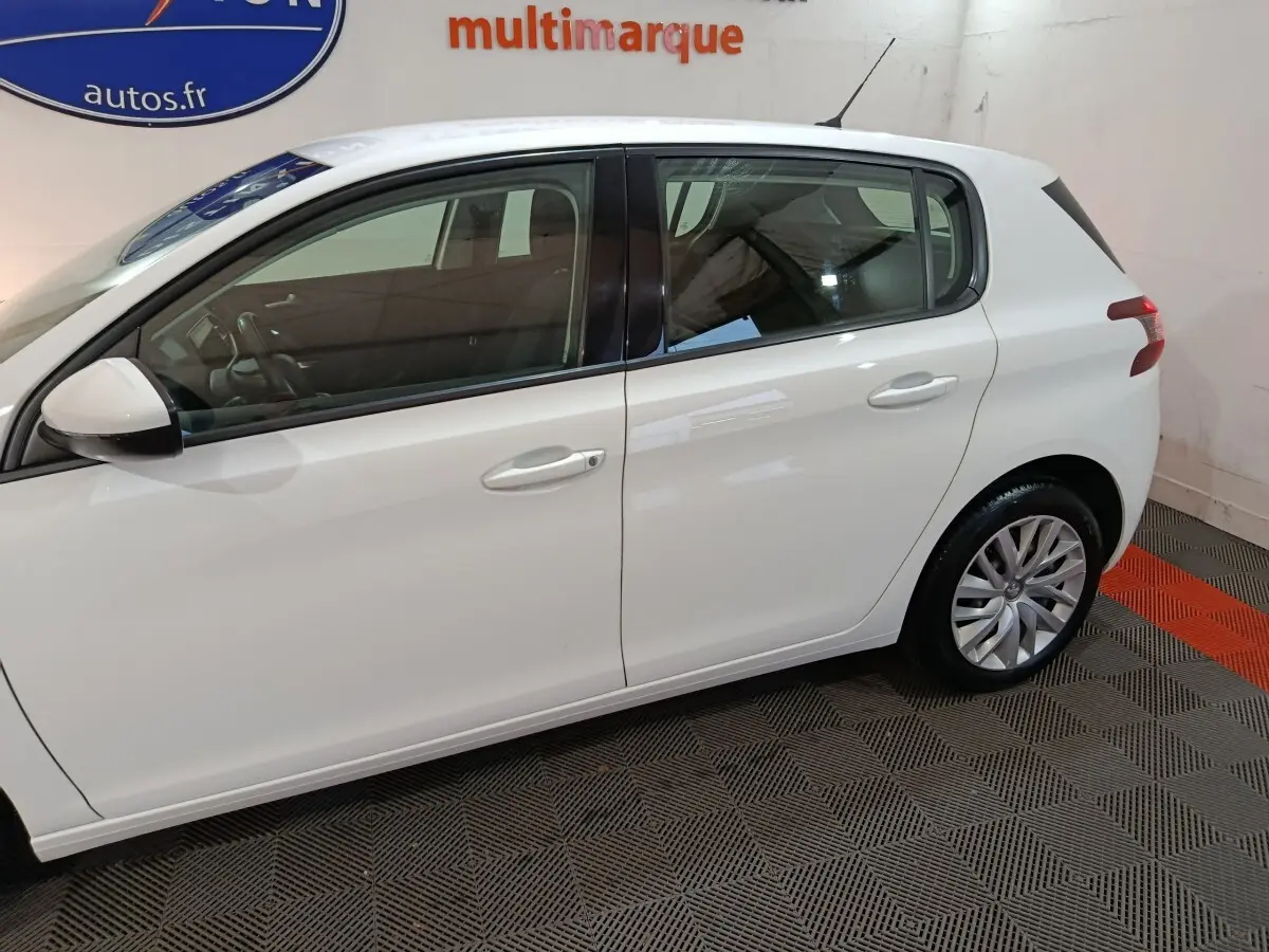 Profil côté gauche d'une Peugeot 308 blanche de 2021, mettant en valeur ses lignes épurées et ses jantes alliage.