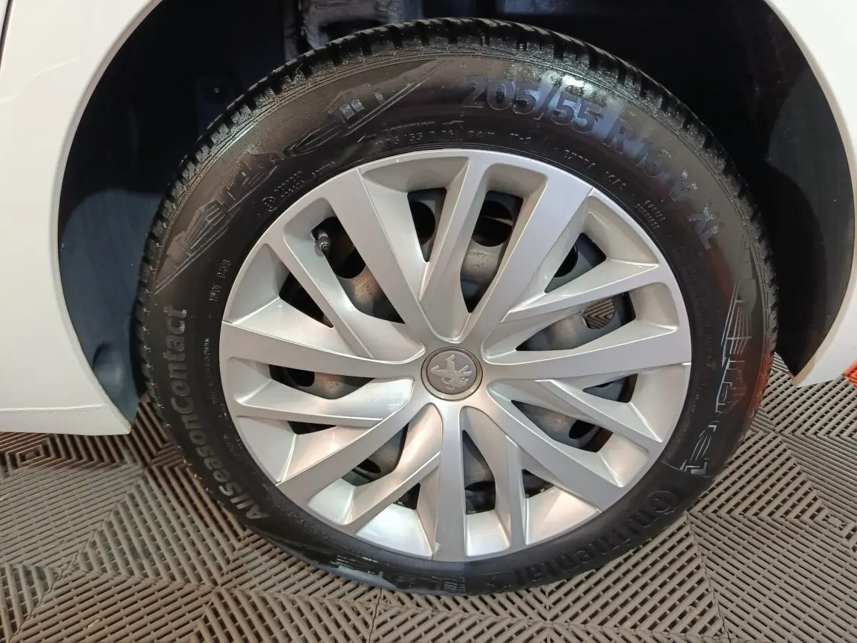 Gros plan sur la roue avant gauche blanche d'une Peugeot 308 BlueHDi 130 S&S PREMIUM PACK avec jante argentée design.