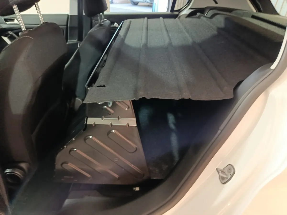 Vue intérieure côté droit du coffre de la Peugeot 308 blanc avec cache-bagages partiellement relevé.