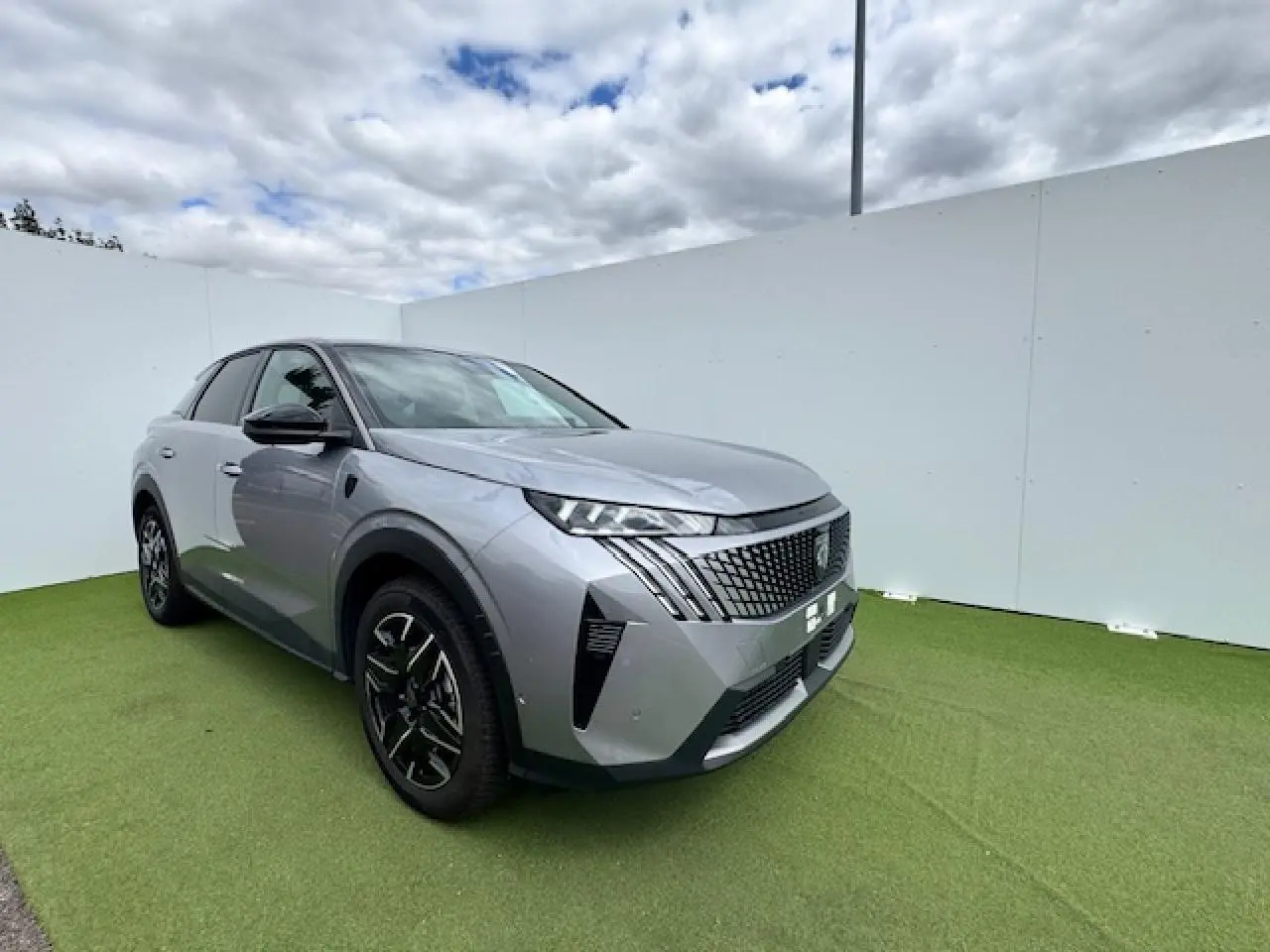 Peugeot 3008 gris Artense toit noir en vue 3/4 avant droit sur fond clair et sol vert.