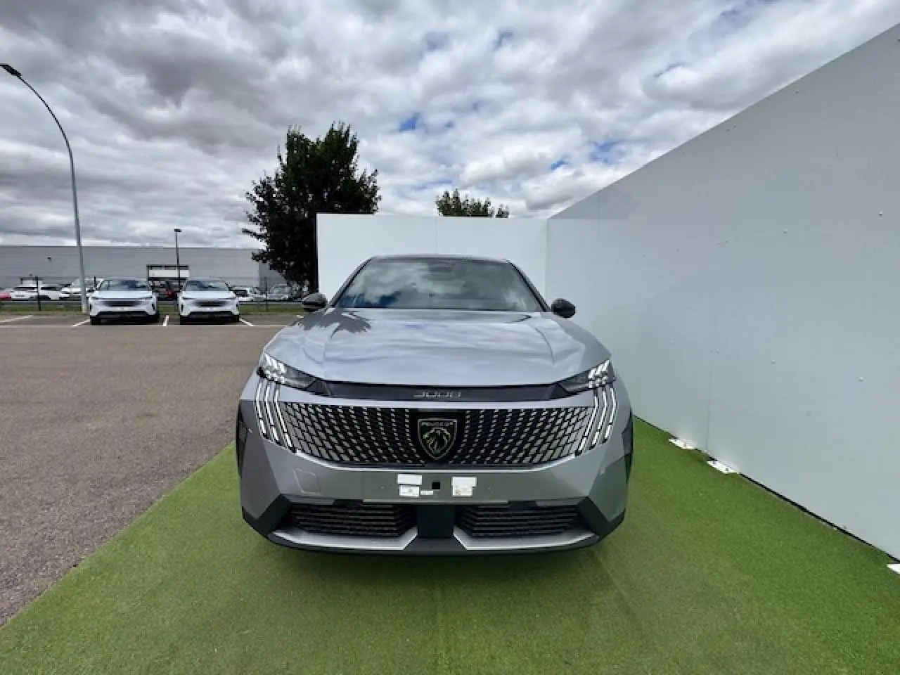 Vue avant d'un Peugeot 3008 gris Artense avec toit noir, calandre large et logo lion central bien visible.
