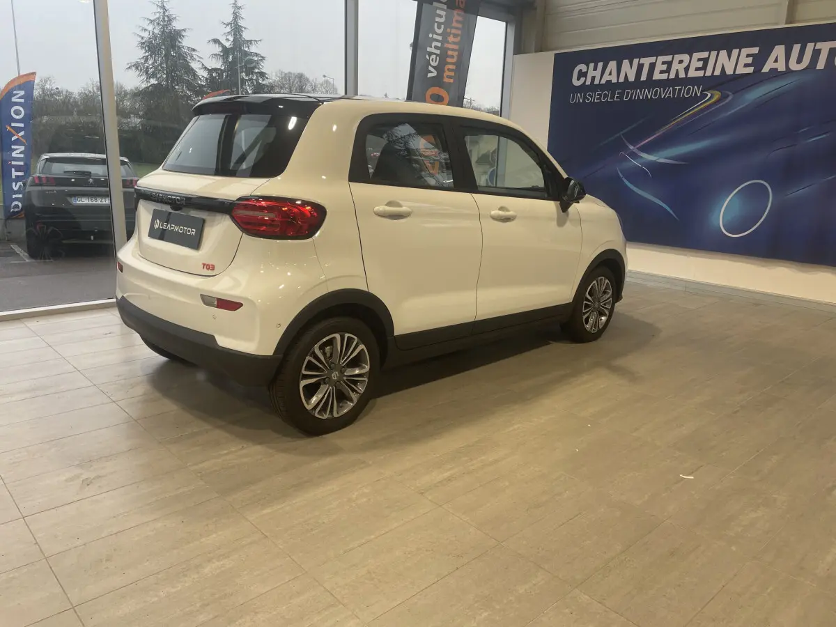 Vue 3/4 arrière droite d'une LEAPMOTOR T03 Luxury blanche, avec feux LED et jantes alliage en showroom.