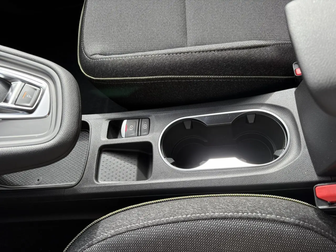Gros plan sur la console centrale noire avec porte-gobelets et bouton de frein à main électrique du Renault Symbioz 2025.