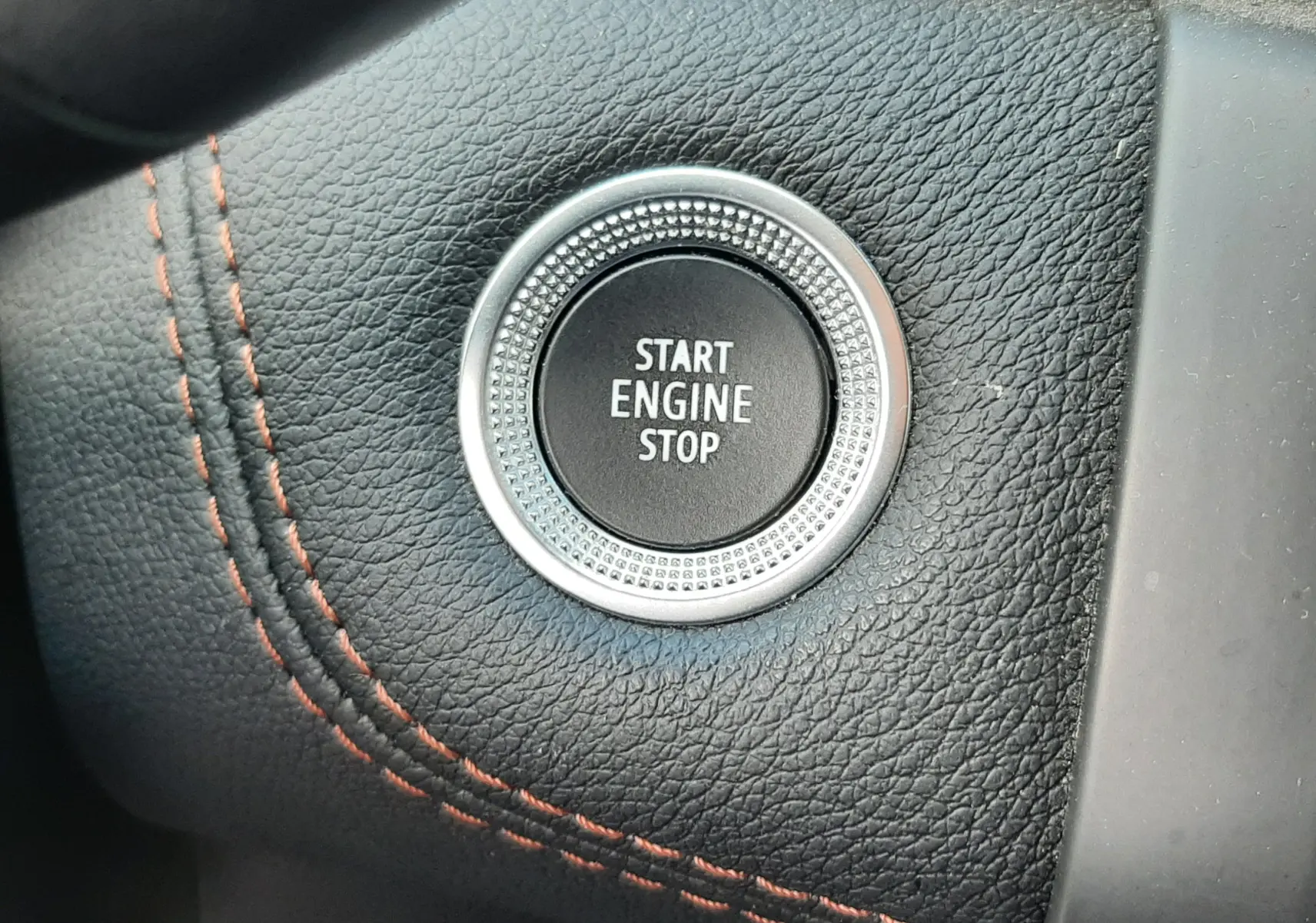 Bouton démarrage moteur rond sur tableau de bord noir avec surpiqûres rouges dans Renault Captur 2020.