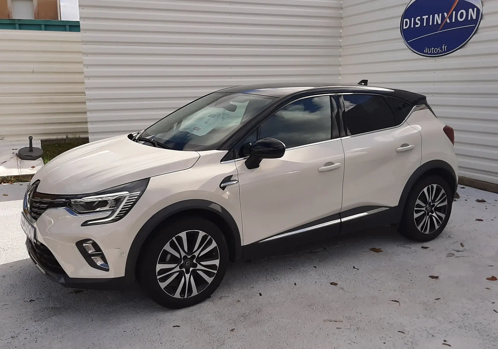 Renault Captur blanc avec toit noir vu en 3/4 avant droit, jantes alliage et vitres teintées.